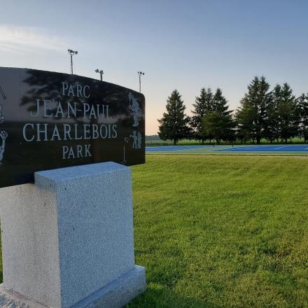 Charlebois Park sign on grassy field, trees in the background.