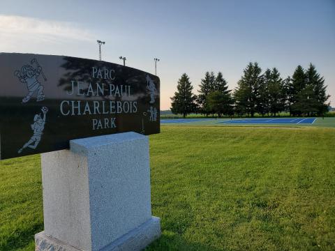 Charlebois Park sign on grassy field, trees in the background.