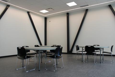Empty room with tables and chairs, light walls, and diagonal supports.