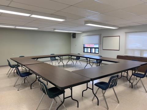 Empty conference room with U-shaped table and blue chairs.