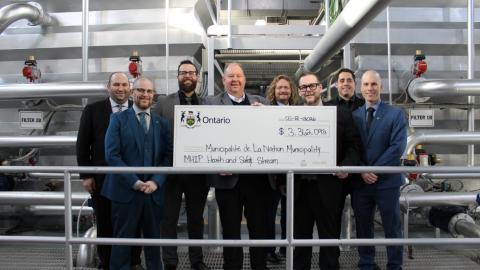 Mayor Francis Brière, MPP Stéphane Sarrazin, and members of The Nation Municipality administration standing inside the Limoges Water Treatment Facility holding a large Ontario funding cheque for the MHIP Health and Safety Stream.