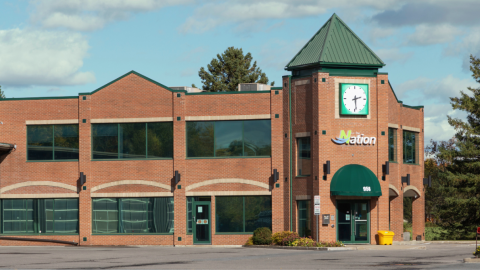 Photo of The Nation Municipality Town Hall building in Casselman, a two-storey red brick municipal building with green roof accents and a clock tower above the main entrance.